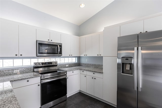 kitchen featuring light stone countertops, white cabinetry, stainless steel appliances, and vaulted ceiling