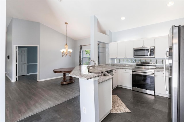 kitchen with white cabinetry, kitchen peninsula, decorative light fixtures, vaulted ceiling, and appliances with stainless steel finishes