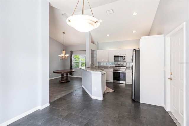 kitchen featuring pendant lighting, white cabinetry, appliances with stainless steel finishes, and vaulted ceiling