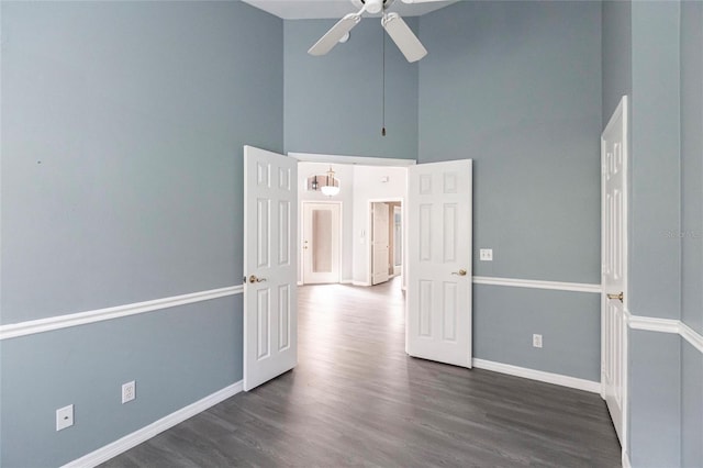 empty room with a high ceiling, dark hardwood / wood-style floors, and ceiling fan