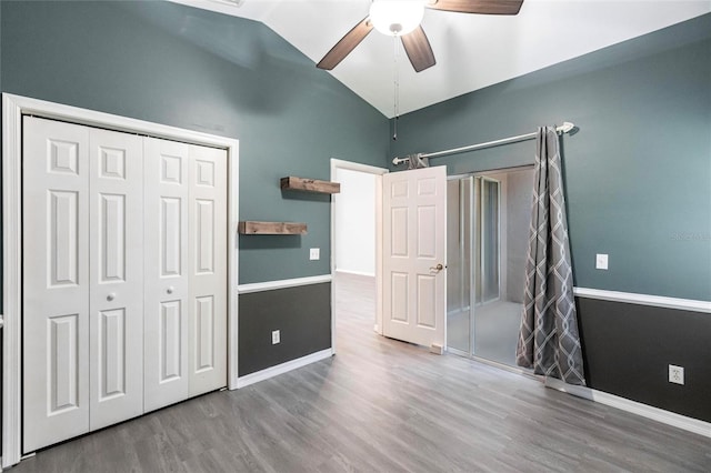 unfurnished bedroom featuring ceiling fan, wood-type flooring, lofted ceiling, and a closet