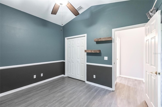 unfurnished bedroom with ceiling fan, a closet, wood-type flooring, and lofted ceiling