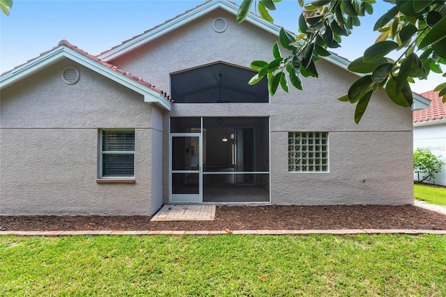 rear view of property with a lawn and a sunroom