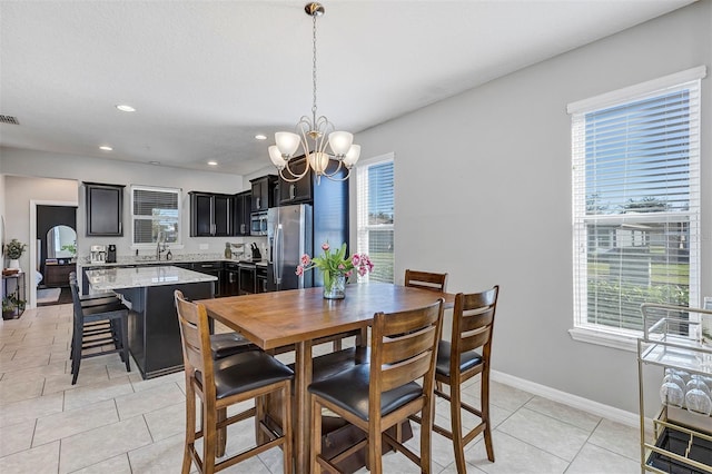 dining room featuring plenty of natural light, light tile patterned floors, sink, and a chandelier