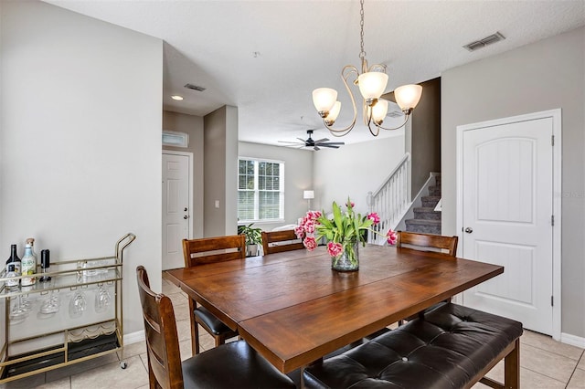 dining room featuring light tile patterned floors, ceiling fan with notable chandelier, and a textured ceiling