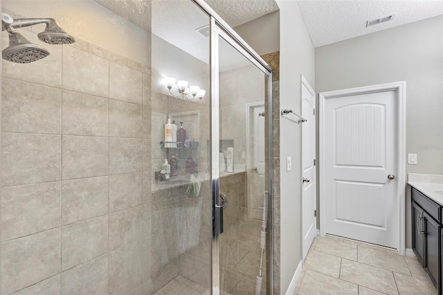 bathroom with tile patterned flooring, vanity, a shower with door, and a textured ceiling