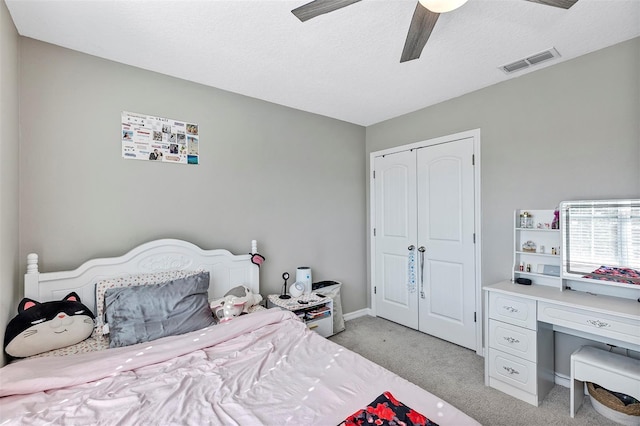 bedroom with ceiling fan, a closet, light colored carpet, and a textured ceiling