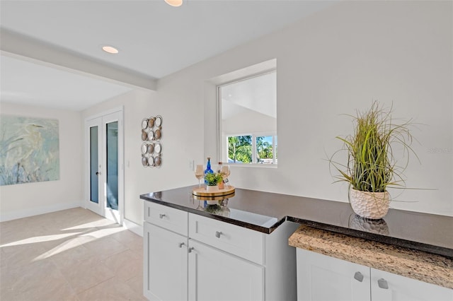 interior space featuring white cabinets, dark stone counters, and light tile patterned floors