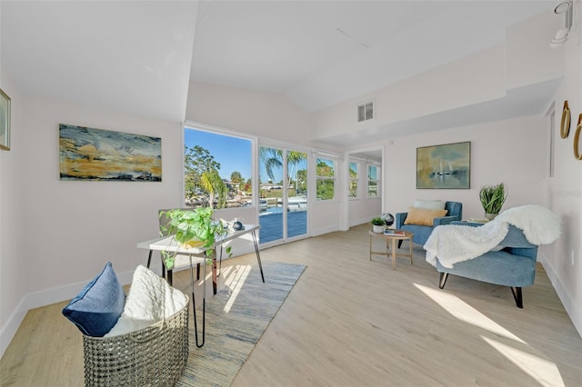 living area featuring vaulted ceiling and light hardwood / wood-style flooring