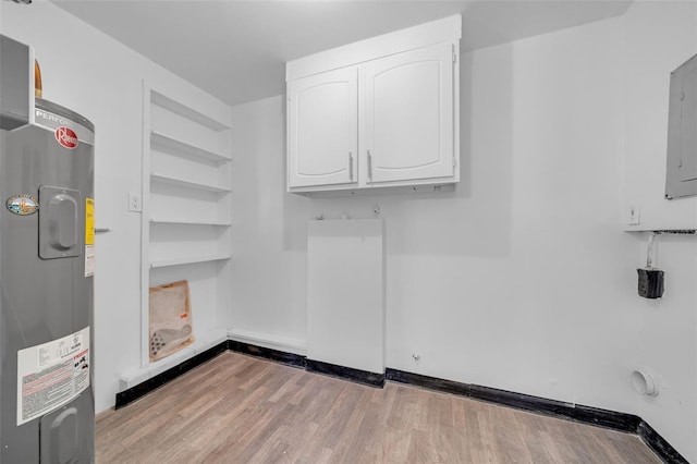 washroom with electric panel, water heater, cabinets, and light wood-type flooring