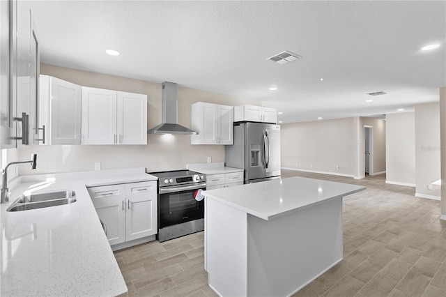 kitchen featuring appliances with stainless steel finishes, a center island, wall chimney exhaust hood, and sink