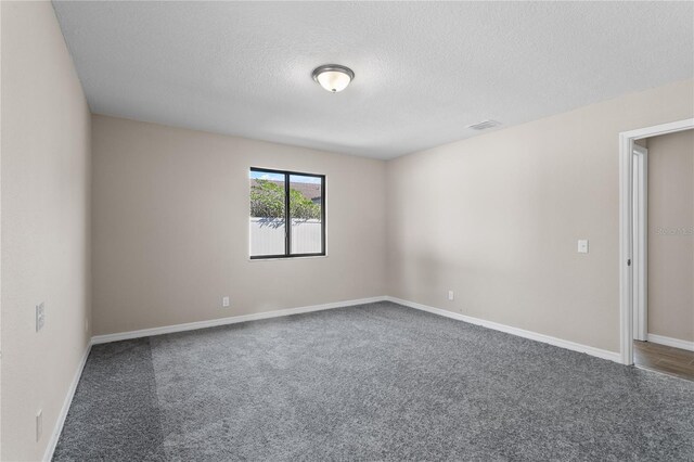 carpeted empty room featuring a textured ceiling