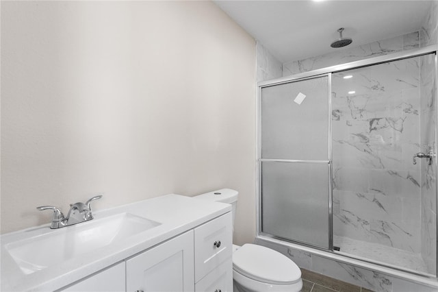 bathroom featuring tile patterned floors, vanity, an enclosed shower, and toilet