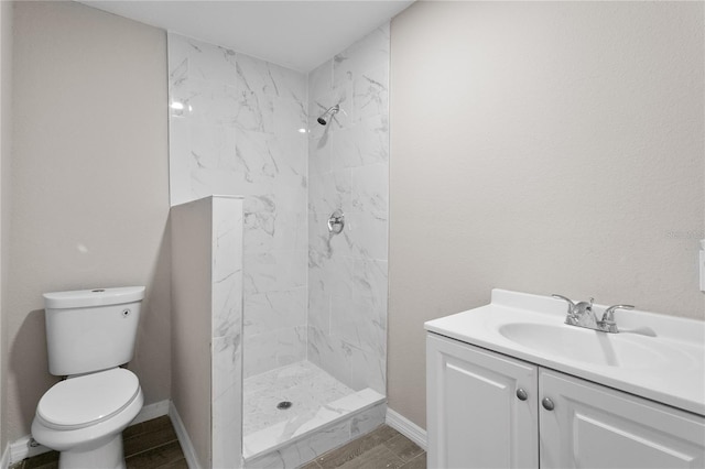 bathroom with tiled shower, vanity, and toilet