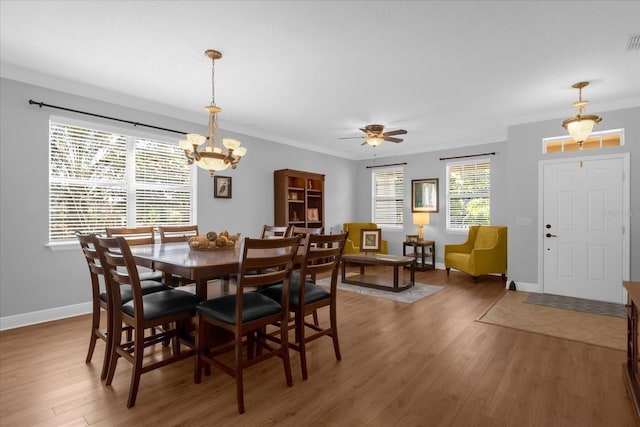 dining room with dark hardwood / wood-style flooring, ceiling fan with notable chandelier, and ornamental molding