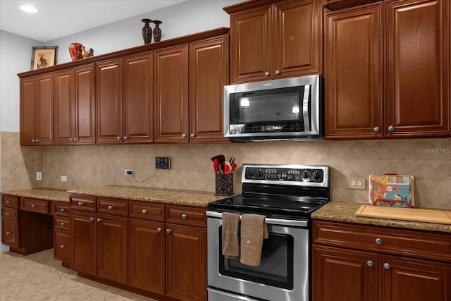 kitchen featuring light stone countertops, light tile patterned floors, appliances with stainless steel finishes, and tasteful backsplash