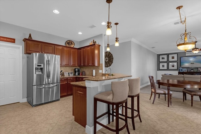 kitchen featuring light stone countertops, a kitchen breakfast bar, stainless steel refrigerator with ice dispenser, kitchen peninsula, and decorative backsplash