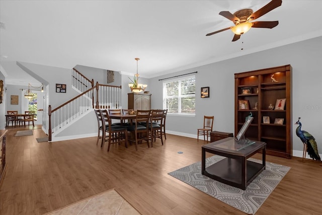 dining space with hardwood / wood-style flooring, ceiling fan with notable chandelier, and ornamental molding