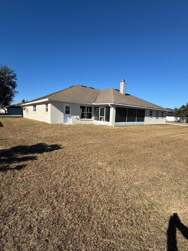 back of property with a lawn and a sunroom