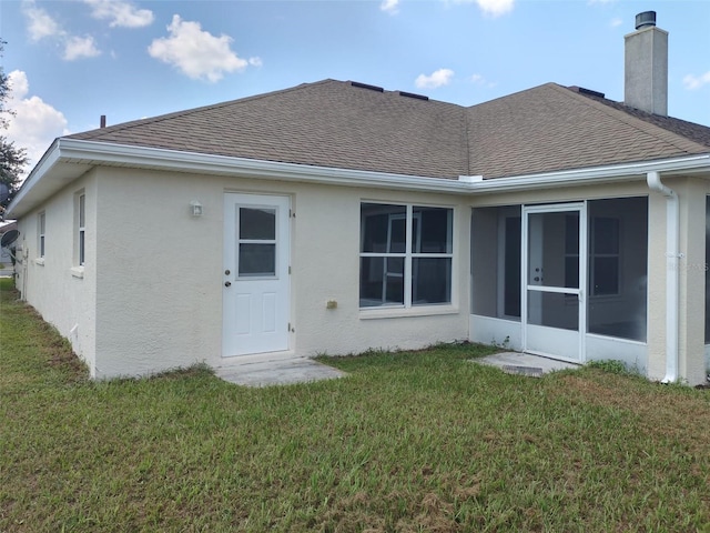 rear view of house with a sunroom and a yard