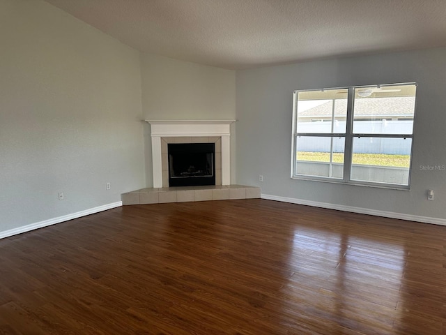 unfurnished living room featuring a textured ceiling, a tiled fireplace, and dark hardwood / wood-style floors