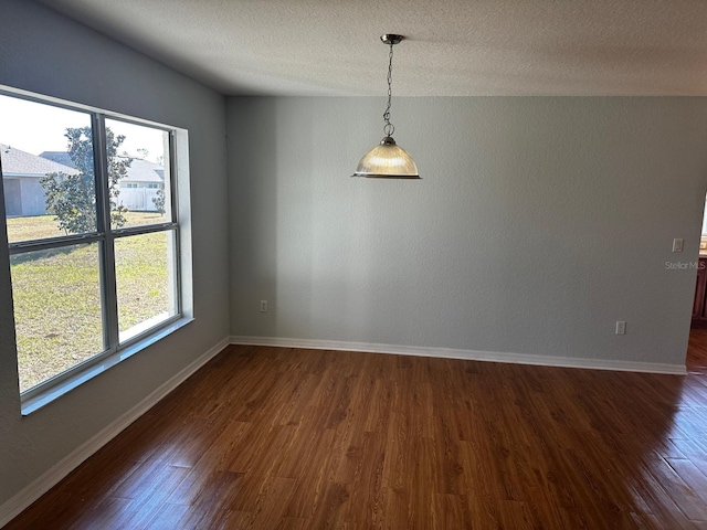 empty room with dark wood-type flooring and a textured ceiling