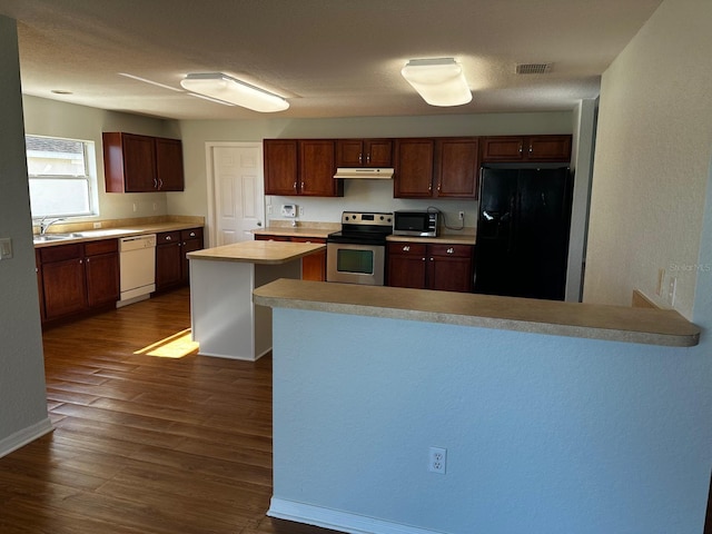 kitchen with dark wood-type flooring, a kitchen island, stainless steel appliances, and sink