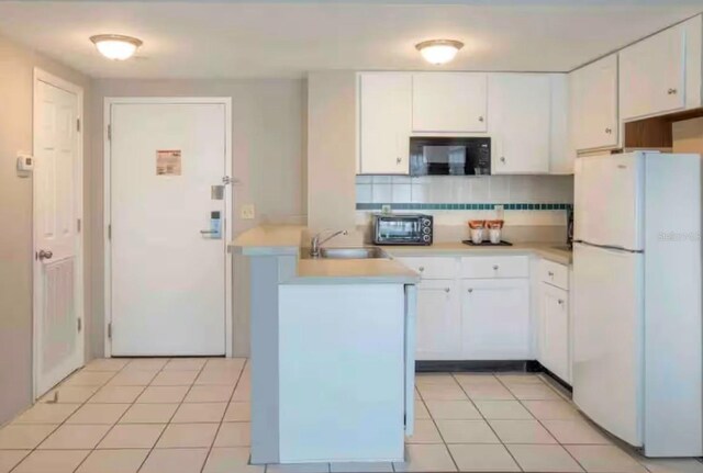 kitchen featuring backsplash, sink, white refrigerator, white cabinets, and light tile patterned flooring