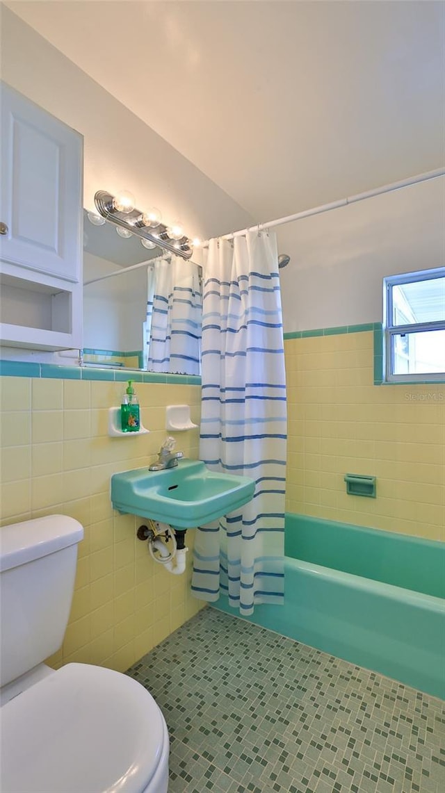 full bathroom featuring tile patterned floors, sink, toilet, shower / bath combo with shower curtain, and tile walls