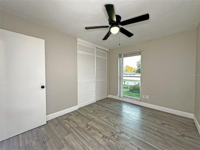 unfurnished bedroom featuring hardwood / wood-style floors, ceiling fan, and a closet