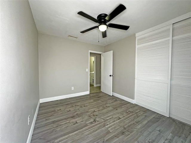 unfurnished bedroom with ceiling fan, a closet, and hardwood / wood-style floors