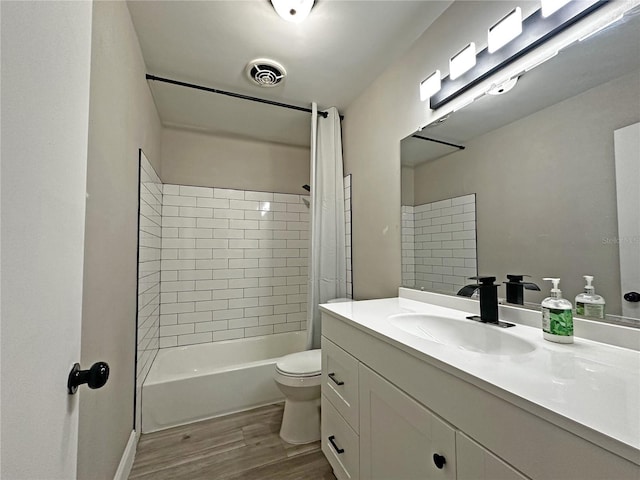 full bathroom featuring vanity, tiled shower / bath combo, hardwood / wood-style flooring, and toilet