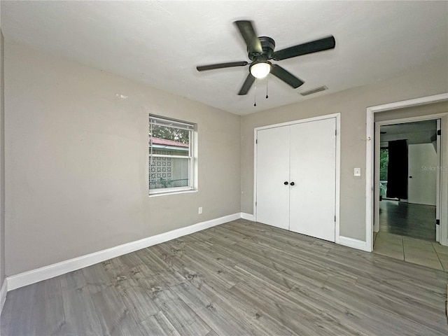 unfurnished bedroom featuring hardwood / wood-style floors, a closet, and ceiling fan