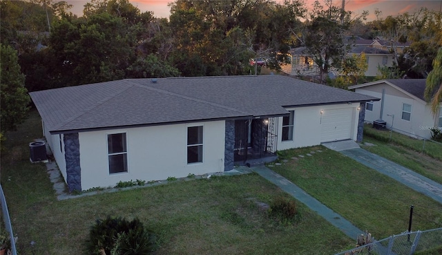 ranch-style house featuring a yard, a garage, and cooling unit