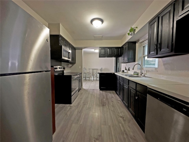 1048 Wakefield Cir, Deltona, FL 32725 - kitchen featuring stainless steel appliances, light countertops, light wood-type flooring, and dark cabinets