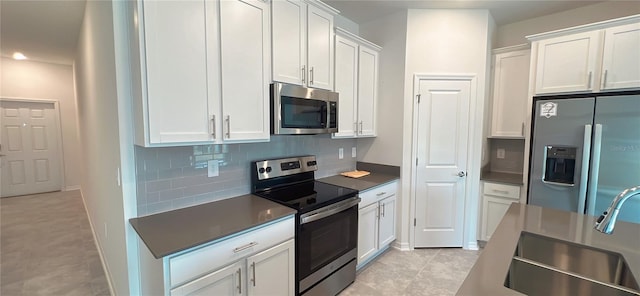 kitchen featuring backsplash, white cabinets, sink, light tile patterned floors, and appliances with stainless steel finishes