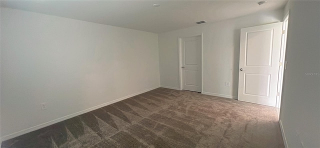 unfurnished room featuring dark carpet