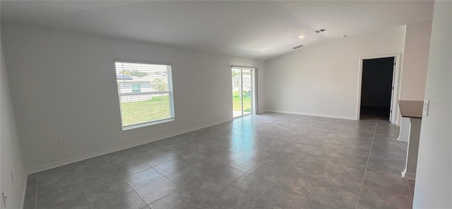 tiled empty room featuring vaulted ceiling