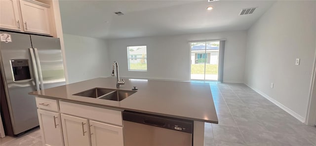 kitchen with appliances with stainless steel finishes, sink, light tile patterned floors, a center island with sink, and white cabinets