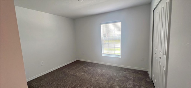 unfurnished room featuring dark colored carpet