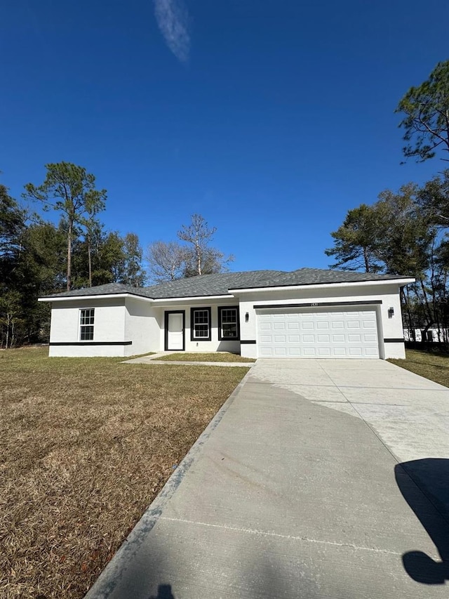 view of front facade with a garage, a front yard, concrete driveway, and stucco siding