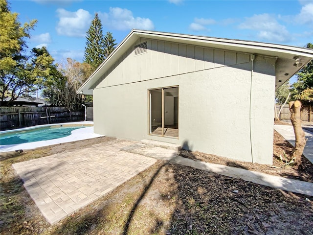 rear view of property with a fenced in pool and a patio