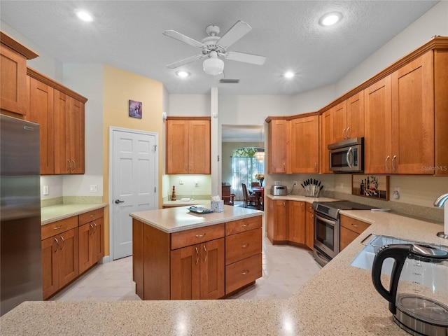 kitchen with light stone countertops, appliances with stainless steel finishes, a textured ceiling, ceiling fan, and sink