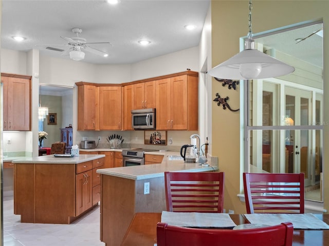 kitchen featuring kitchen peninsula, a textured ceiling, stainless steel appliances, ceiling fan, and sink