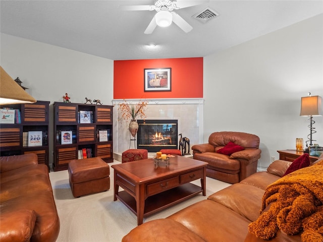 carpeted living room with a tiled fireplace and ceiling fan