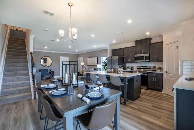 dining room featuring crown molding, light hardwood / wood-style flooring, and an inviting chandelier