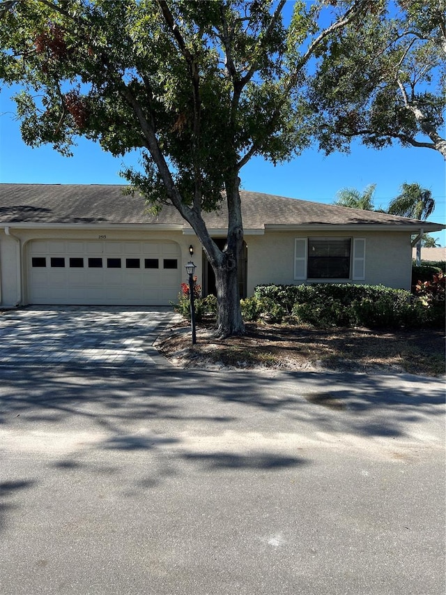 ranch-style house with a garage, driveway, and stucco siding