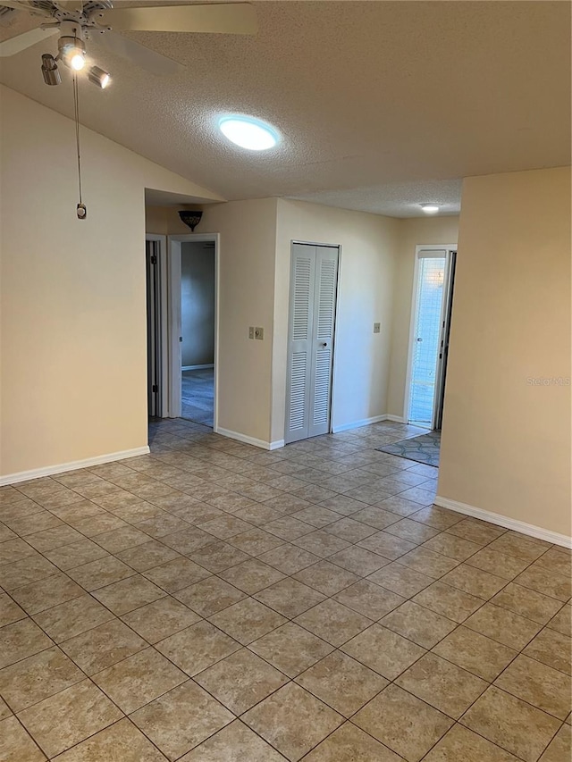 spare room featuring ceiling fan, vaulted ceiling, and a textured ceiling