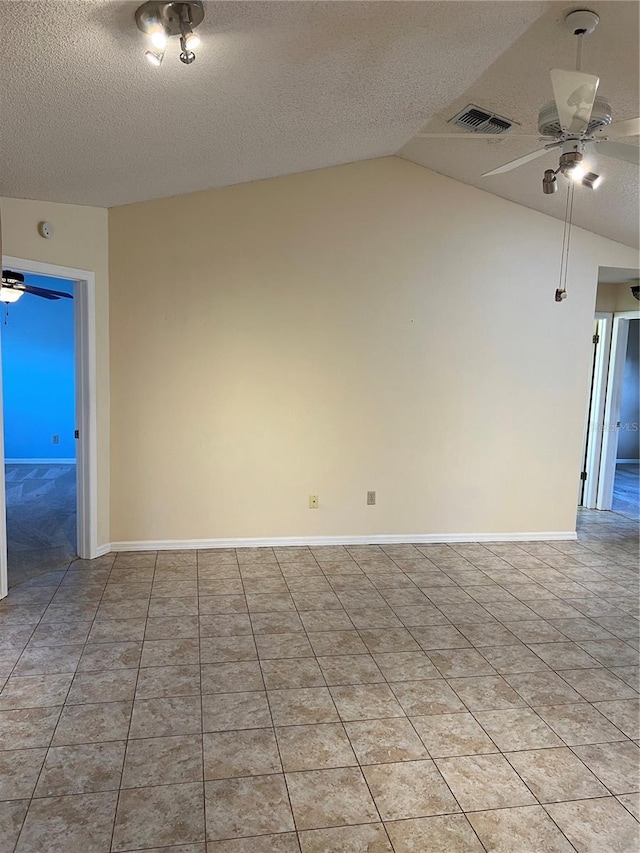 empty room featuring ceiling fan, vaulted ceiling, and a textured ceiling