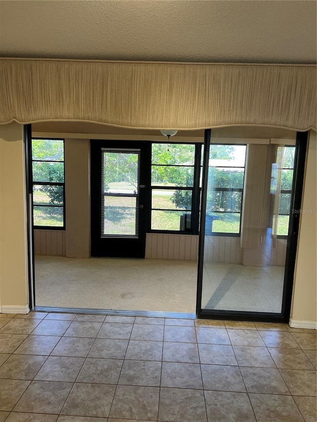 entryway with light tile patterned floors and a textured ceiling